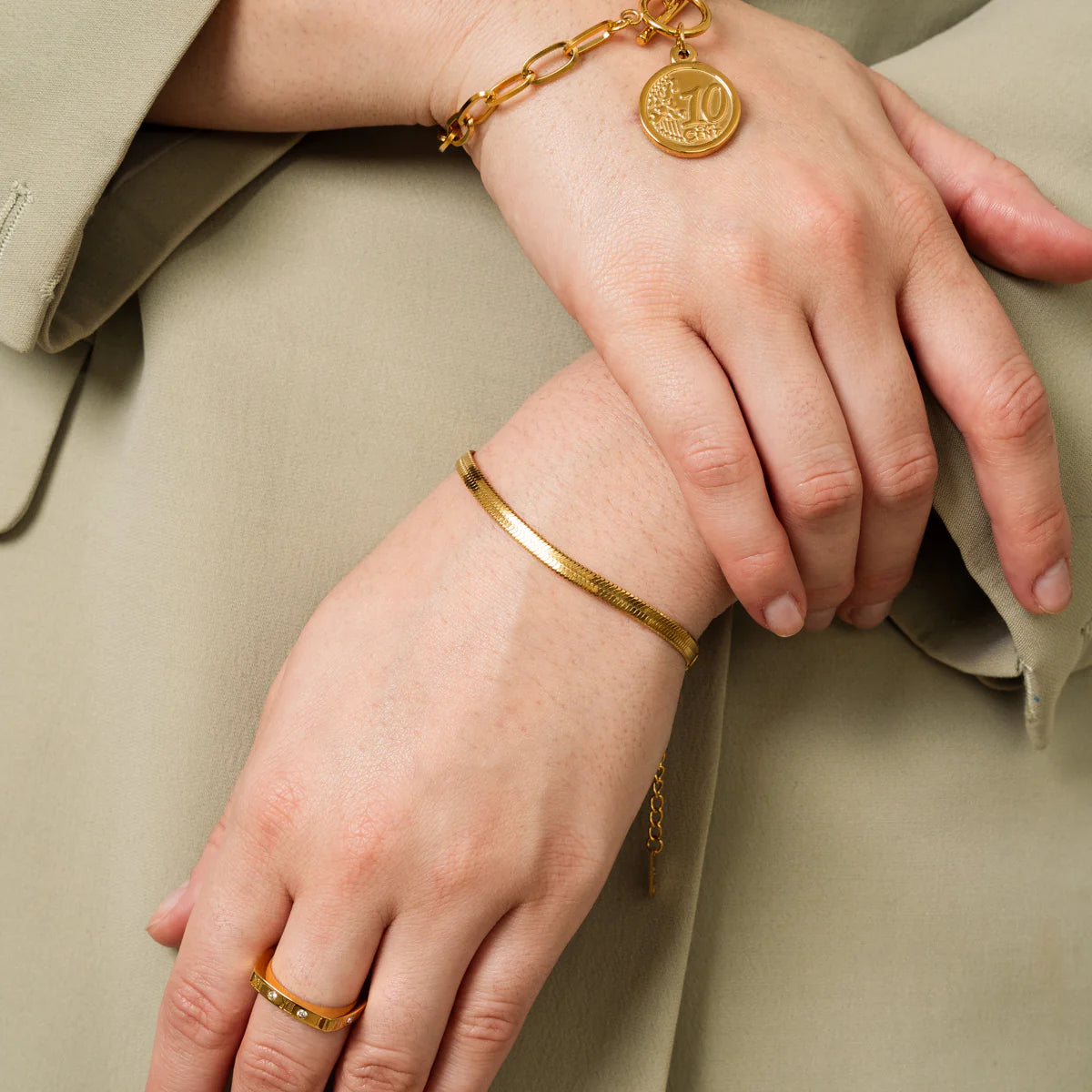 Gold tone snake chain bracelet layered with coin charm bracelet, perfect for elegant and trendy jewelry combinations.