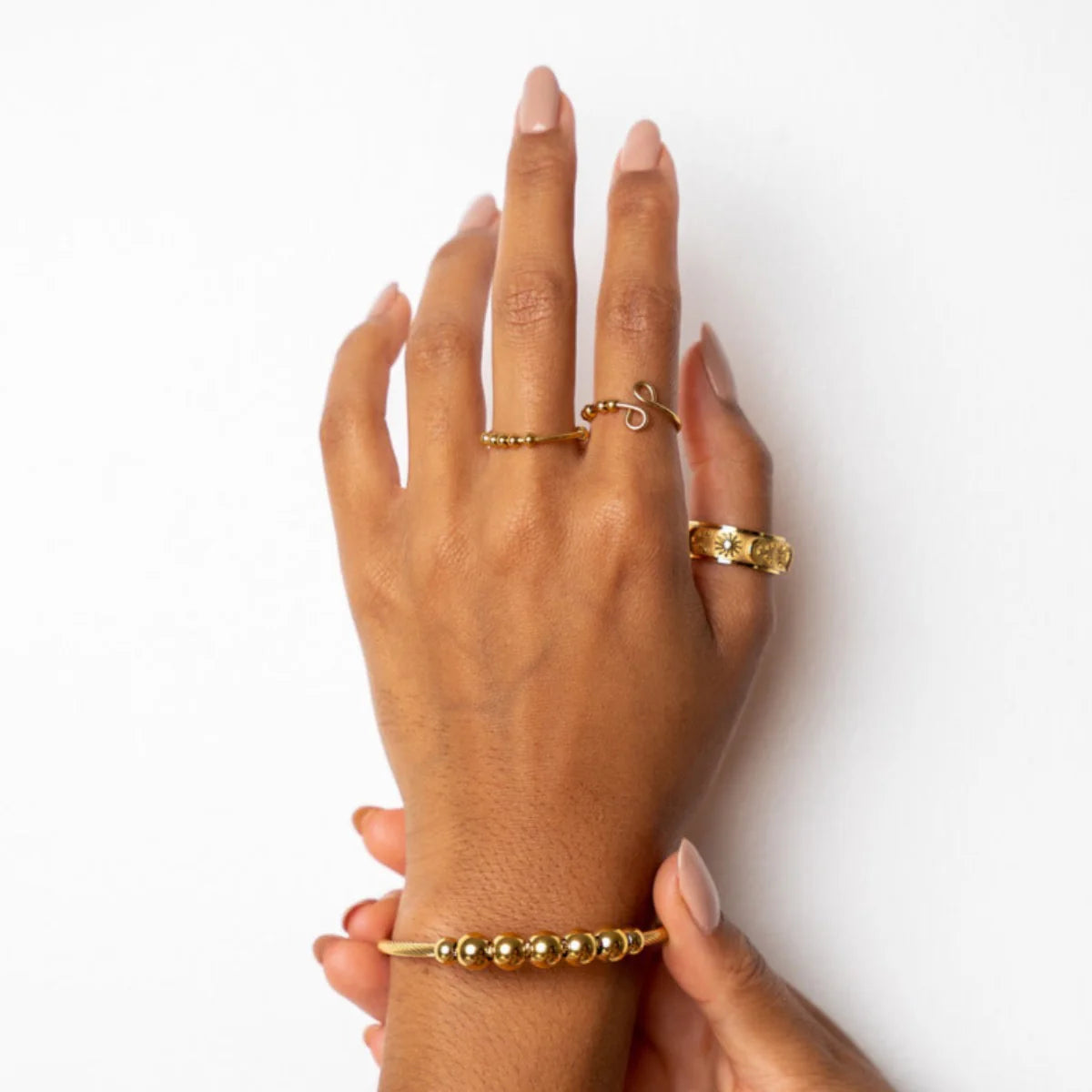 Hand wearing gold tone Eclipse Fidget Ring with rotating outer band for calming stress relief.