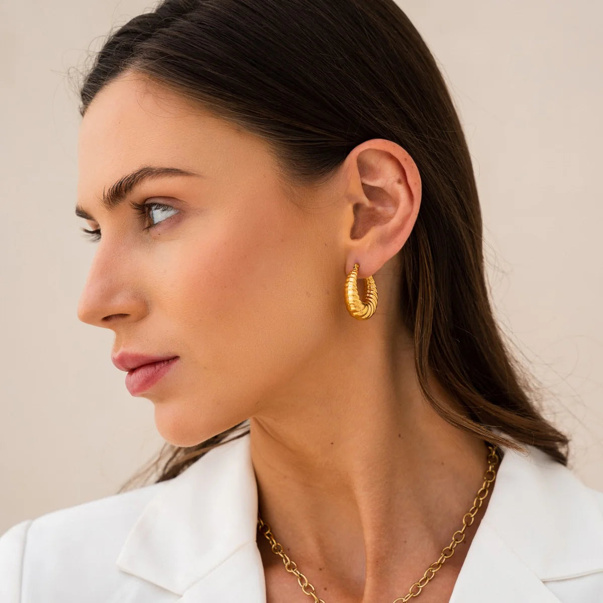Side profile of model showcasing Croissant Hoops - Trendy Gold Earrings. Textured gold tone adds a chic touch to any outfit.