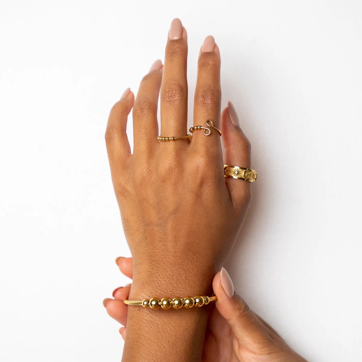 Close-up of hand adorned with Gold Fidget Bangle-Anxiety Relief and matching rings, highlighting fashionable anxiety support jewelry.