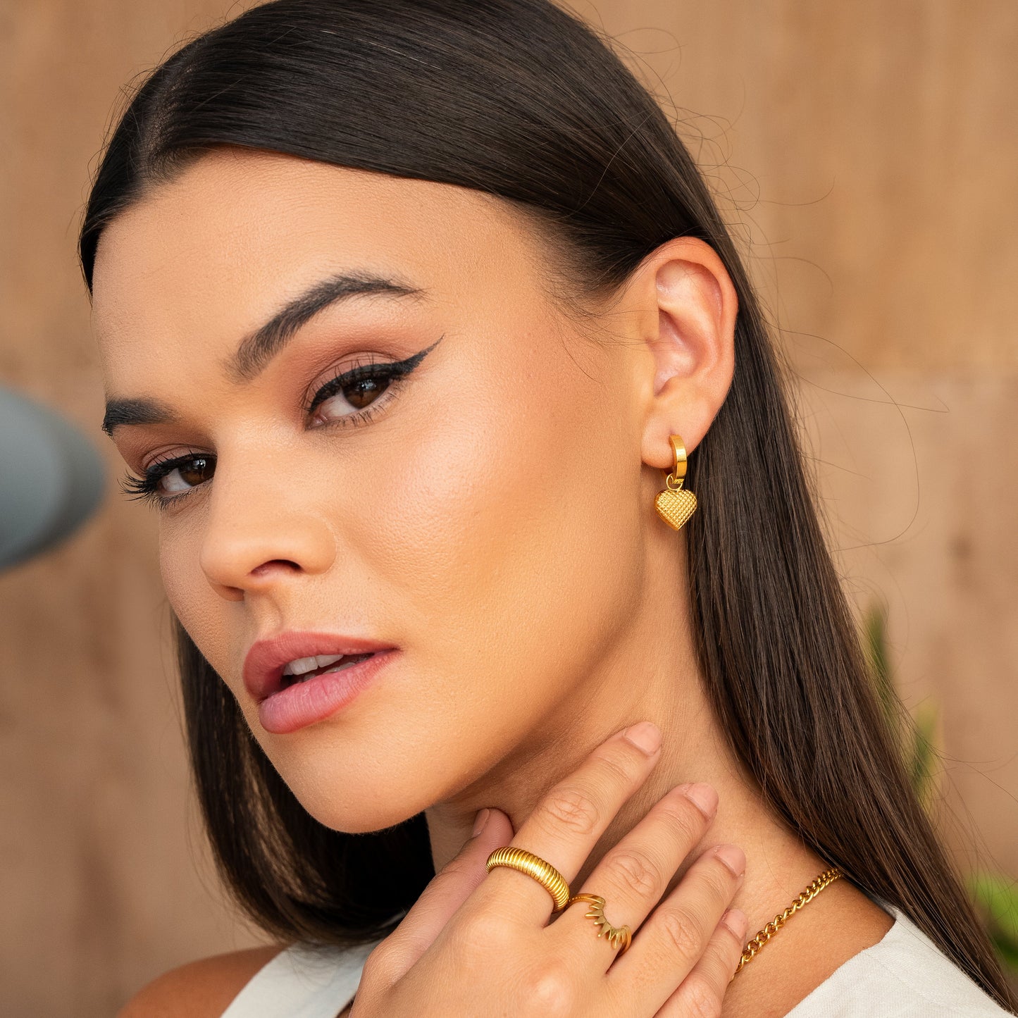 Model styling Heart Huggies - Gold Tone Tone Earrings with matching gold accessories, emphasizing the 8mm water-resistant heart design.
